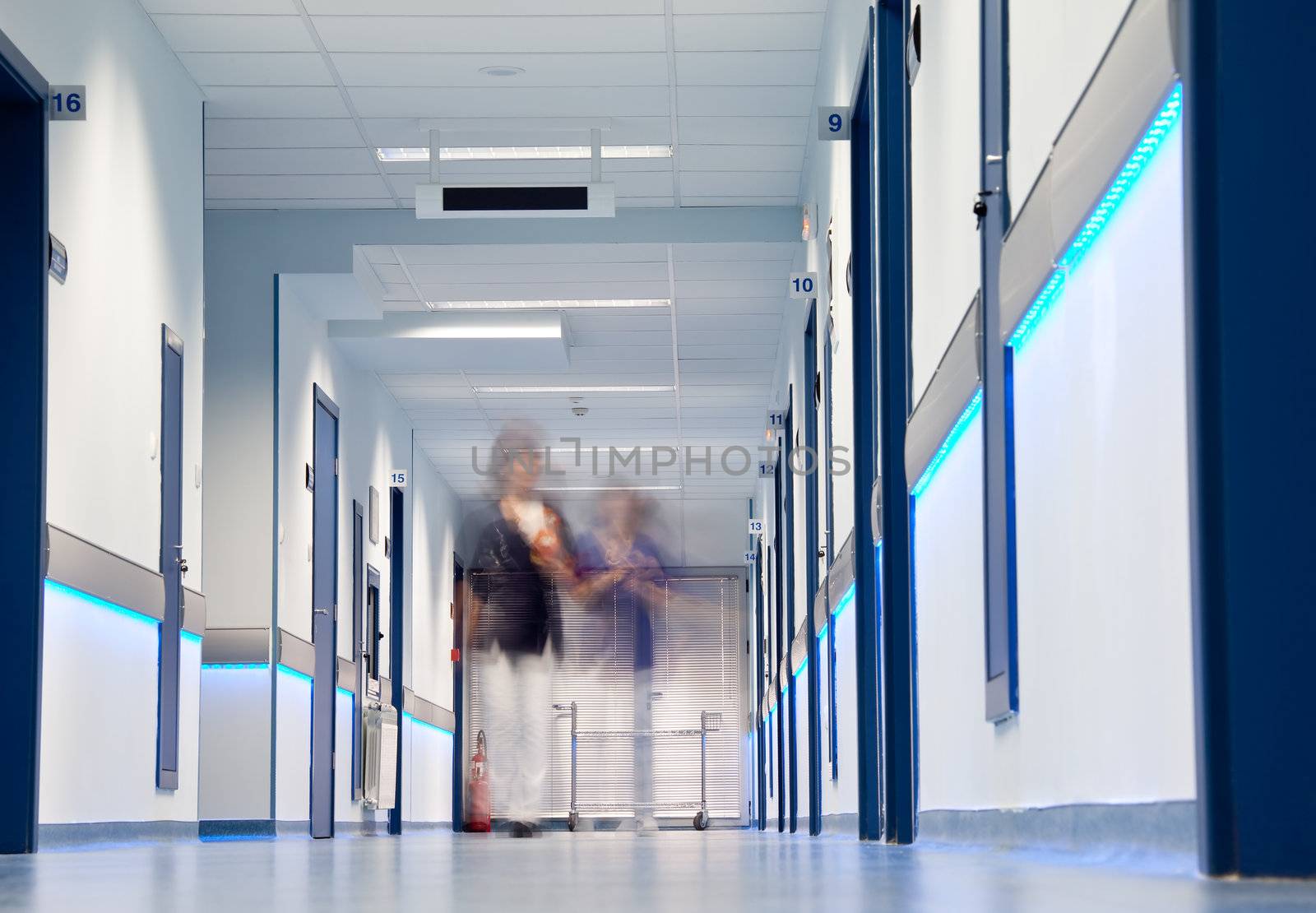 blurred figures of nurses walking down a hospital corridor