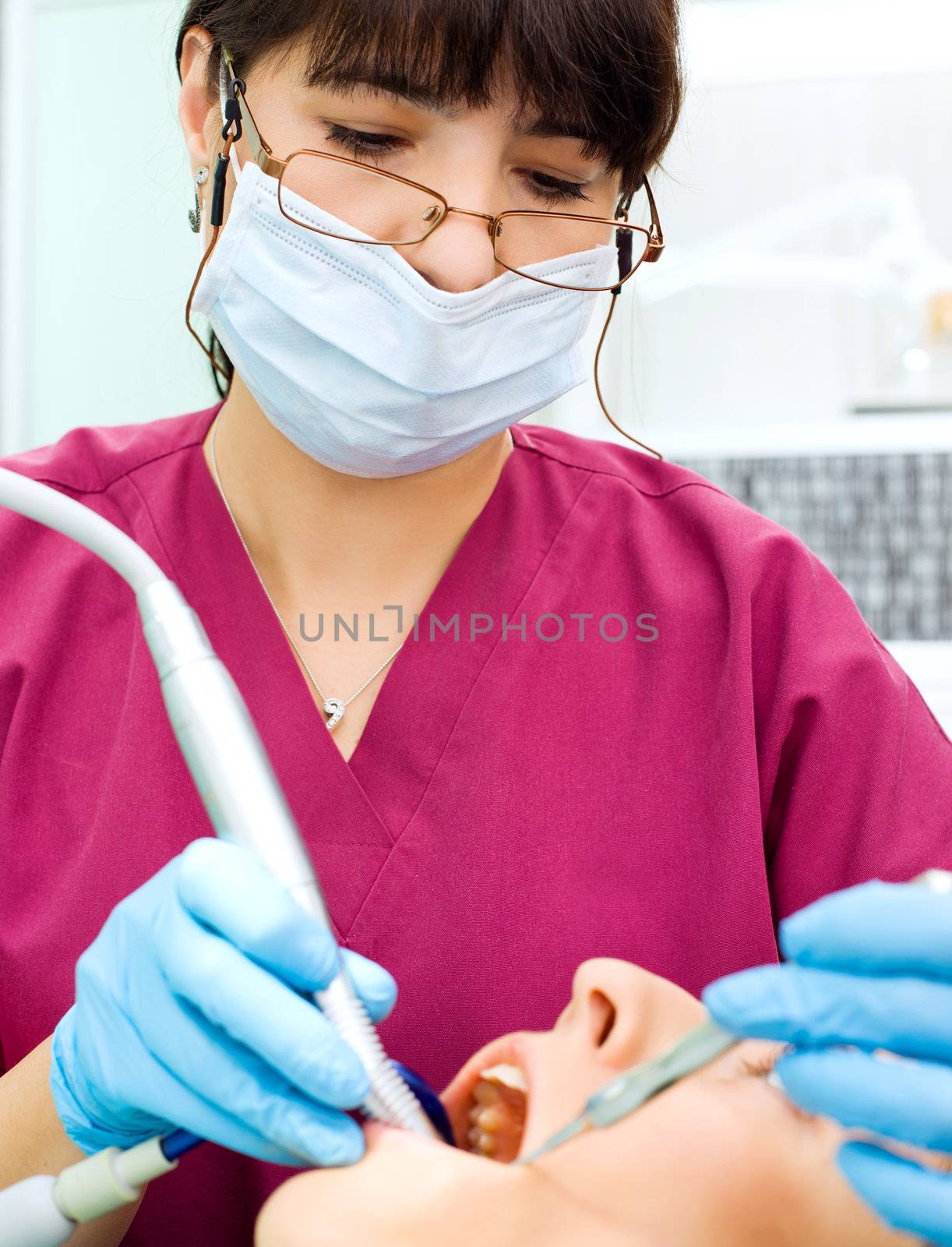 Female dentist wearing protective mask and gloves working on patient