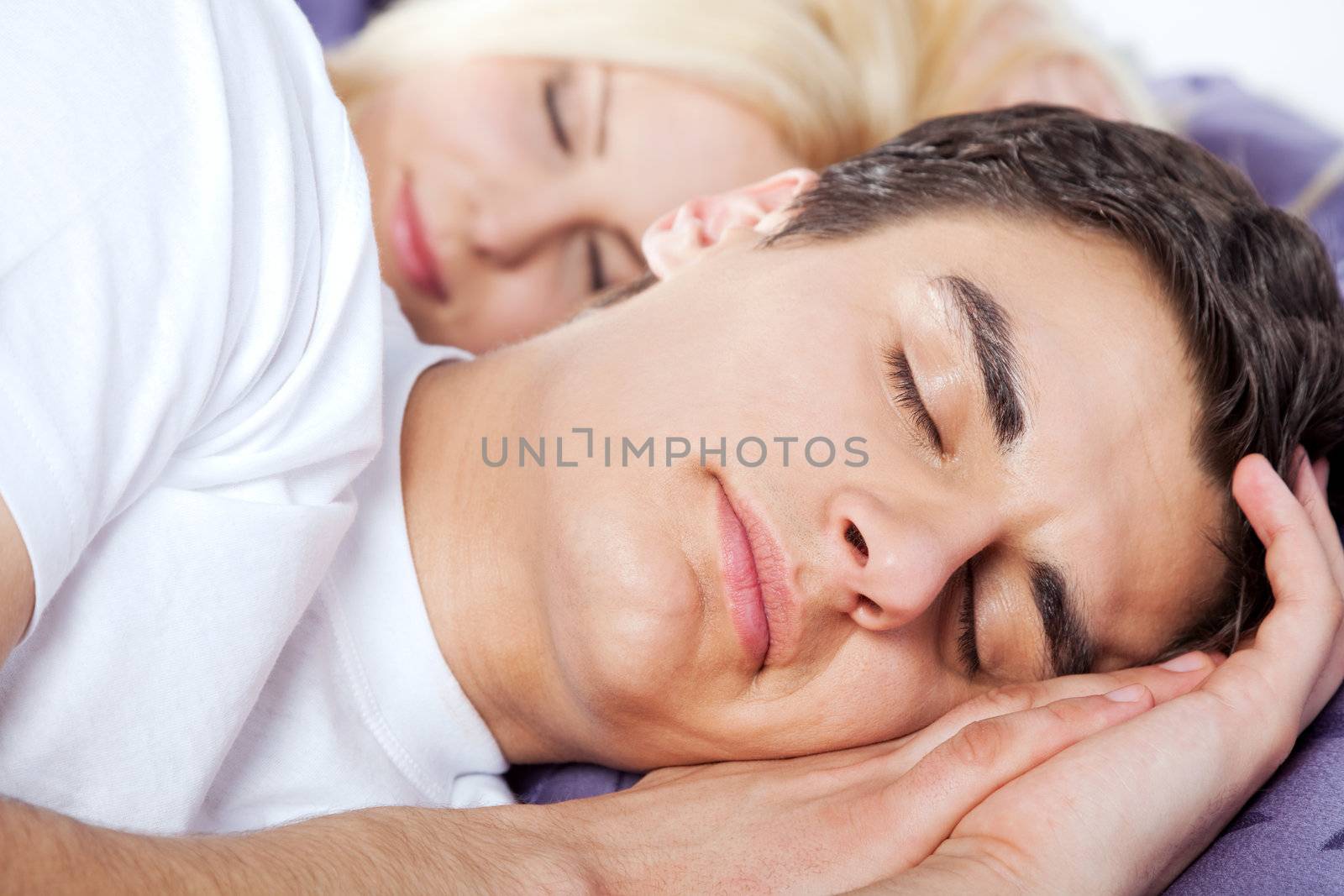 Close-up of a young couple sleeping late together, man on focus