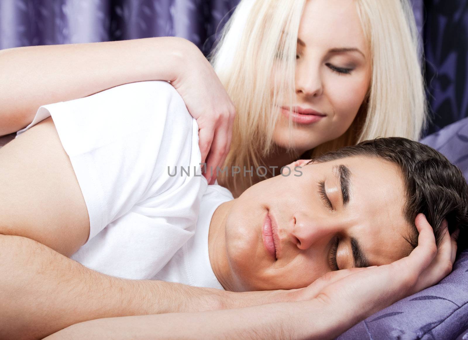 Young beautiful woman gently waking up sleeping man