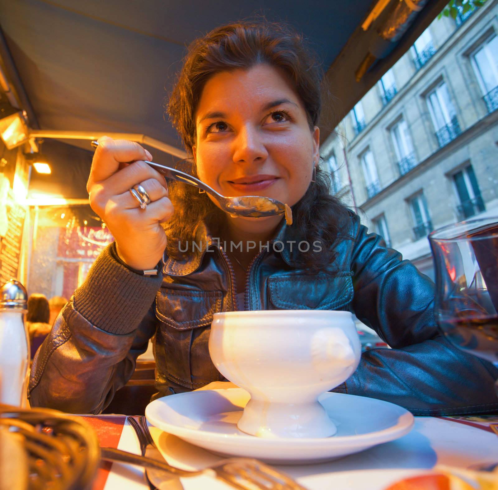 smiling female sitting in restaurant, eating soup