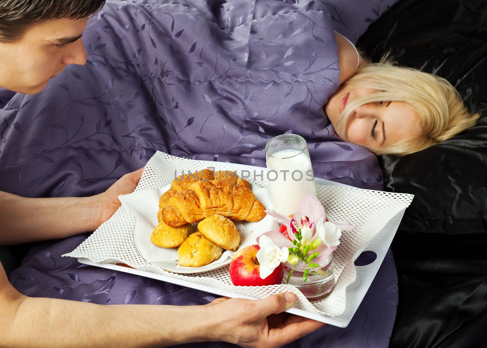 young male serving a breakfast in bed to woman