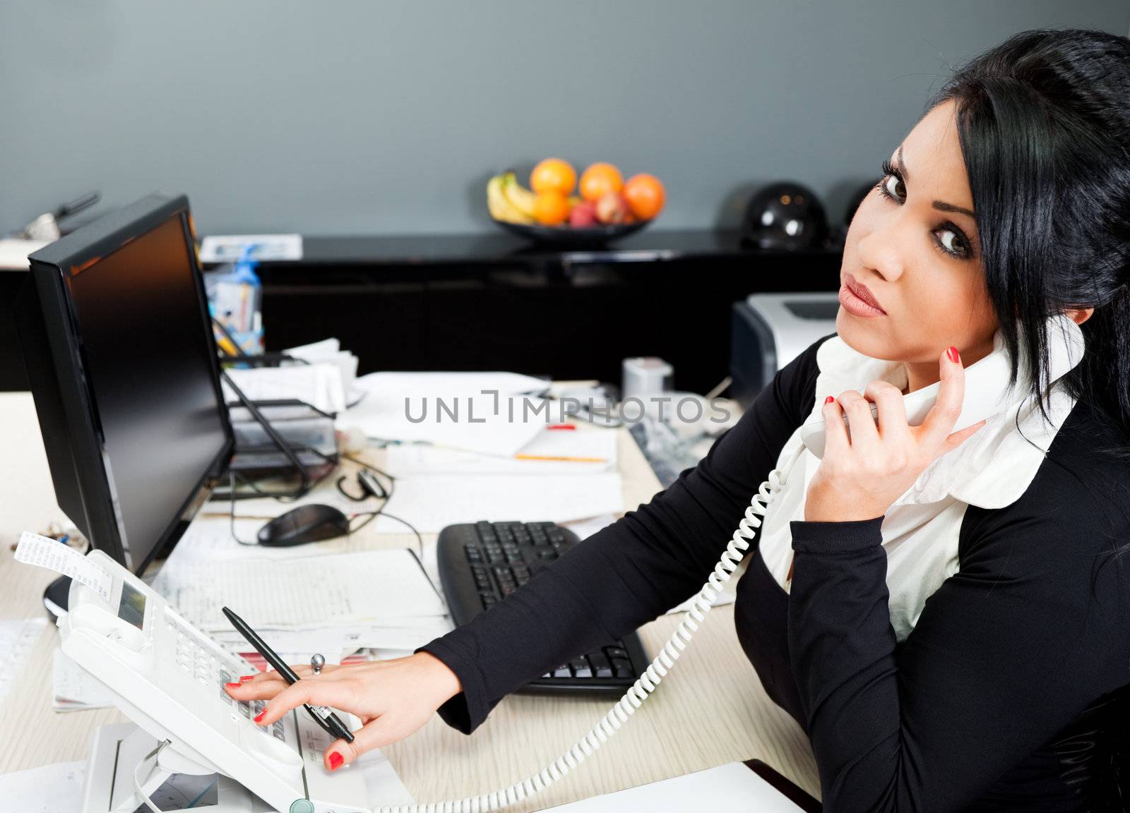 young hispanic female speaking on a phone in the office