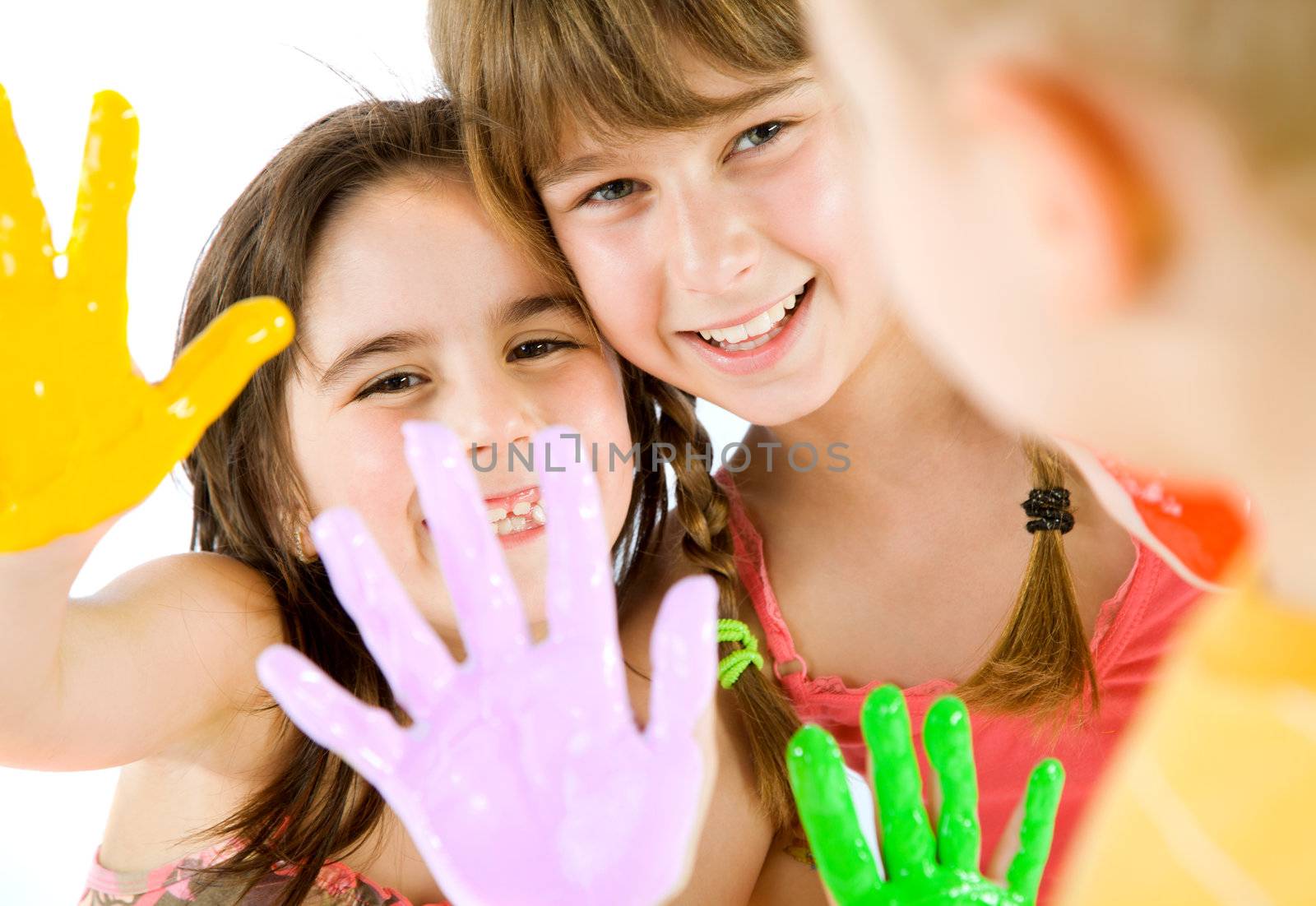 Close-up of two little girls showing their painted colourful hands to a boy, focus on girls