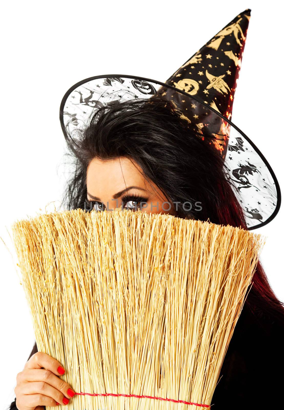 young female dressed up as a witch hiding behind broom