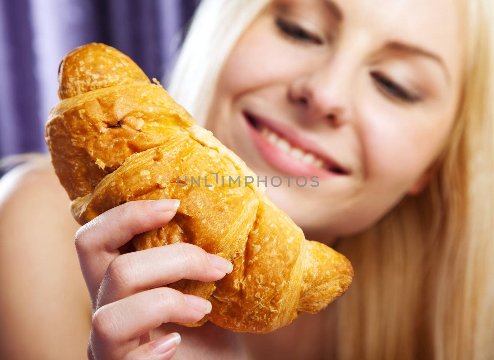 young woman smiling and holding a fresh croissant
