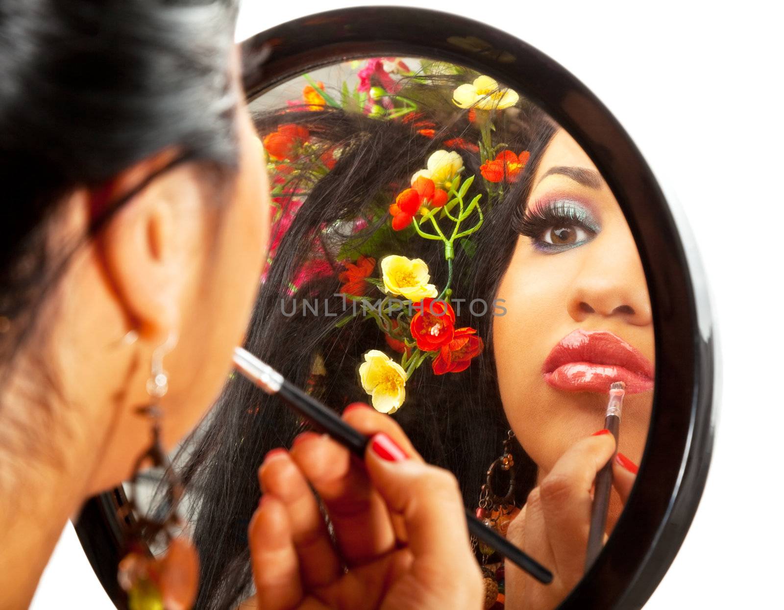 reflection in a mirror of a beautiful hispanic female applying lipstick