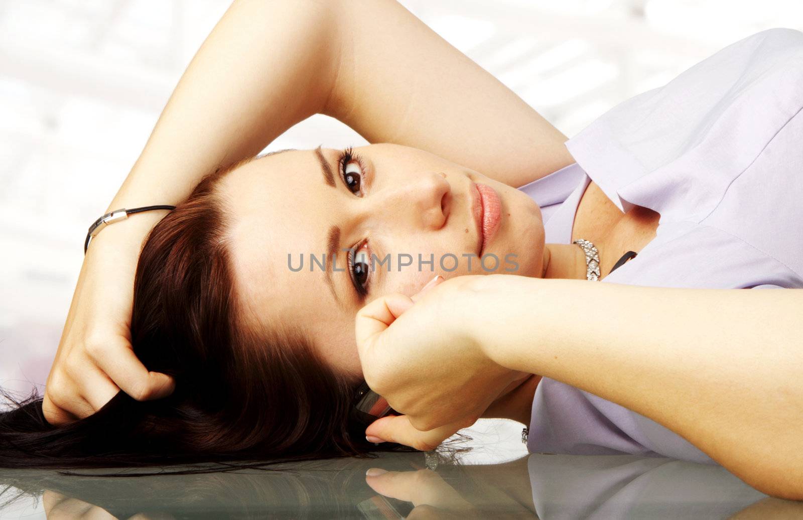 close-up of a female lying on a desk while talking on her cellphone