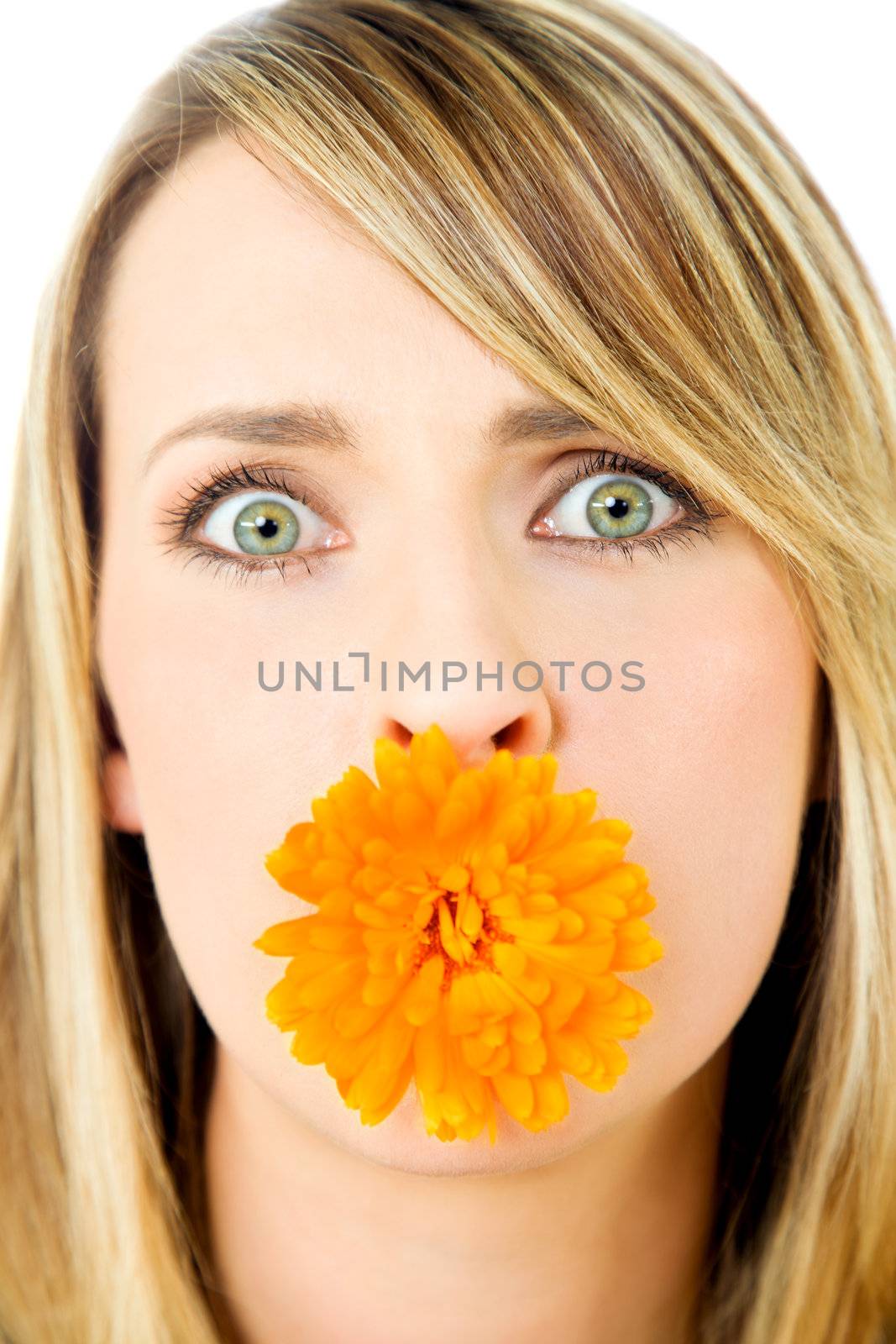 Close-up of beautiful blond female with marigold flower in mouth, staring at camera