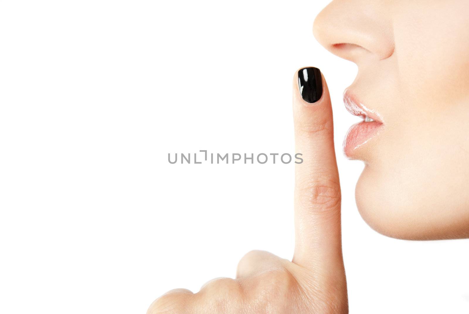 Close-up of female index finger with black fingernail put on her lips, making silence sign