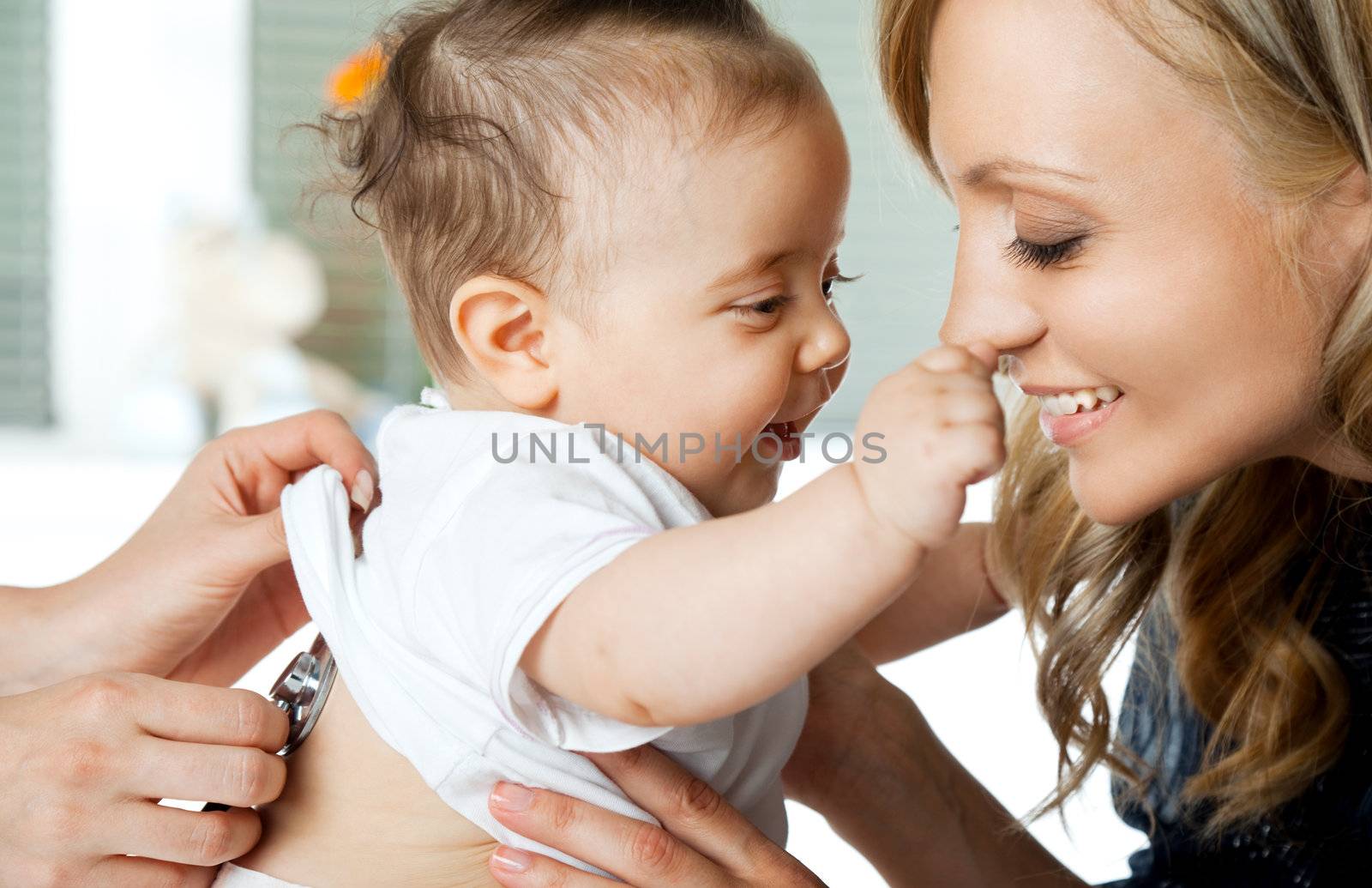 Close-up of baby girl being examinated by doctor, playing with mother
