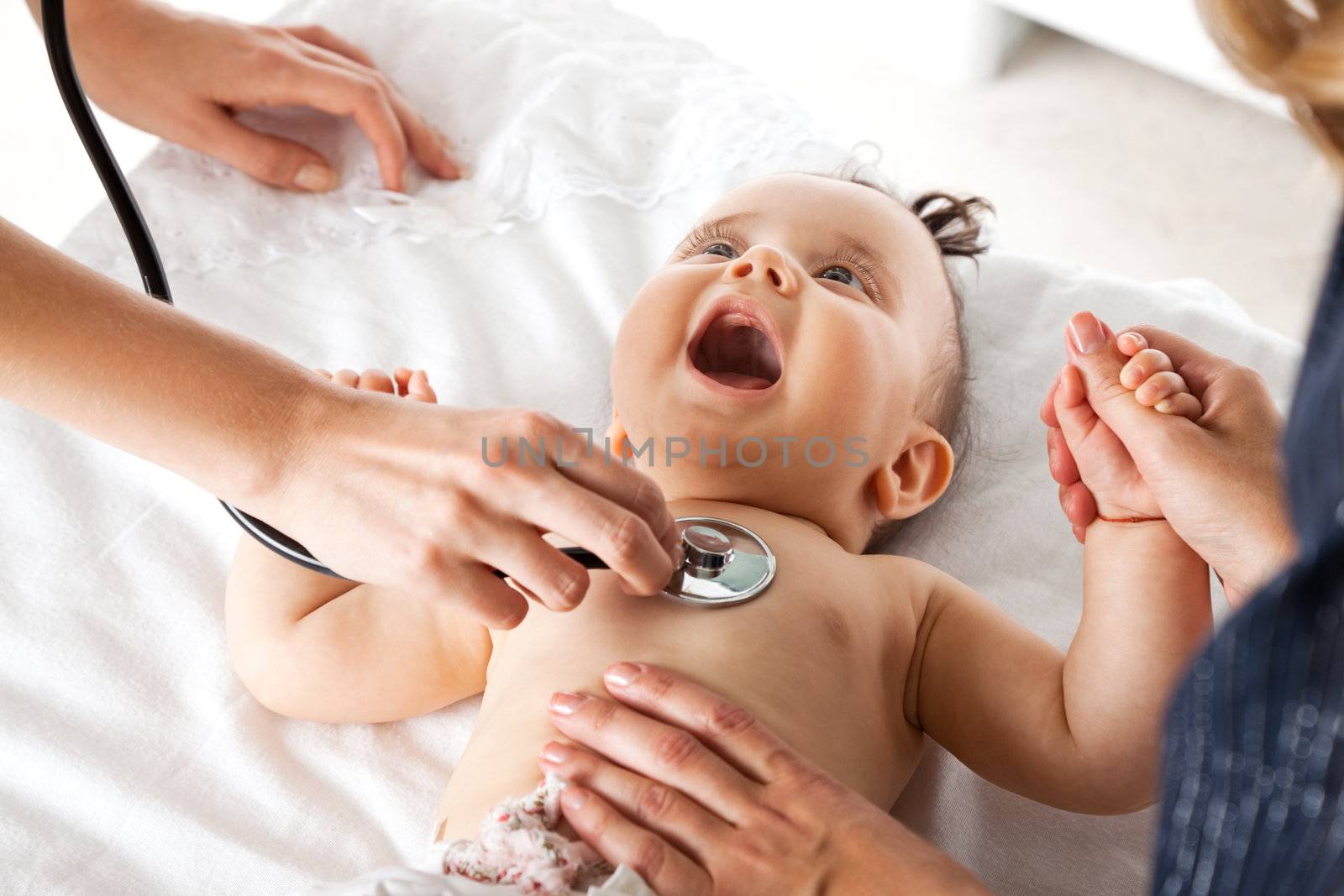 Sweet baby examinated with stethoscope, holding mother's hand