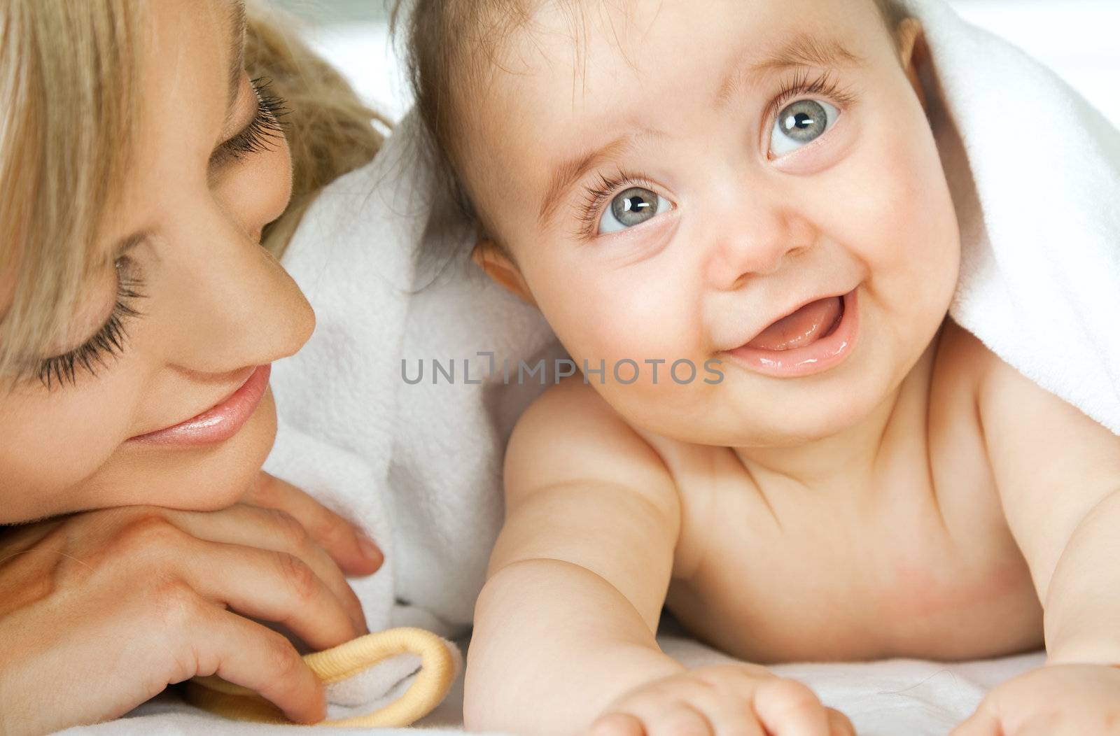 Close-up of adorable little baby face smiling lying next to her mother