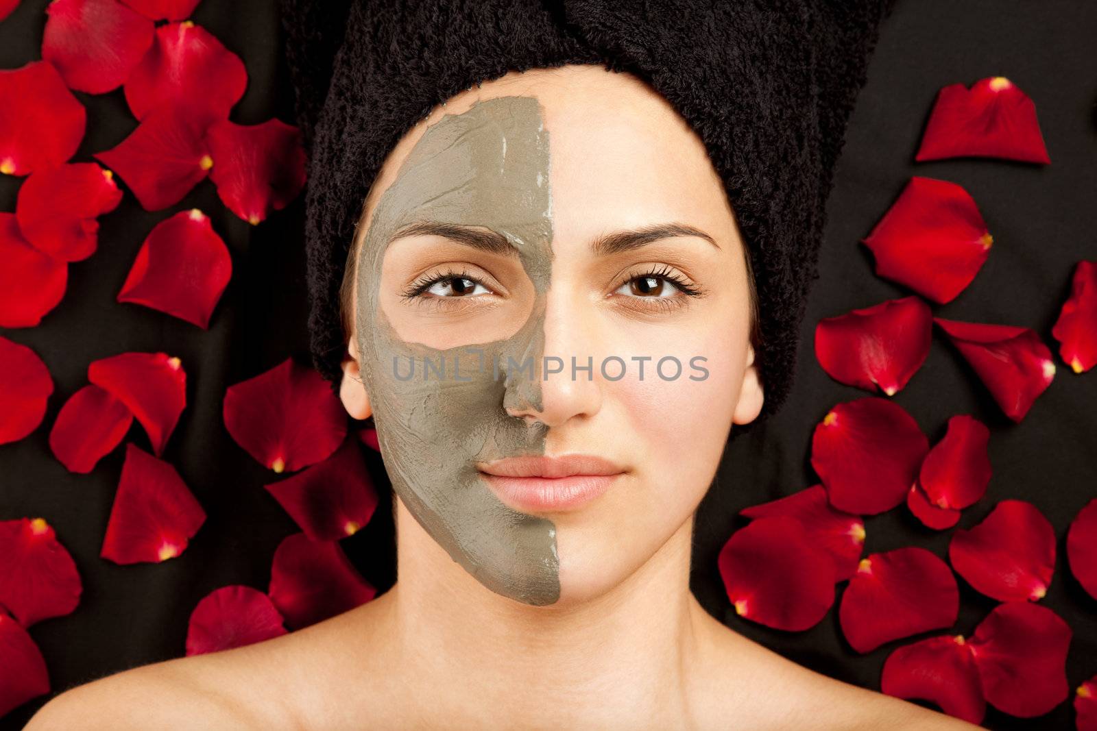 young beautiful woman having a clay mask on half of her face