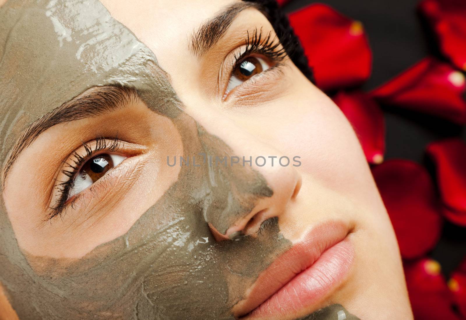 close-up of a young woman face half with clay mask