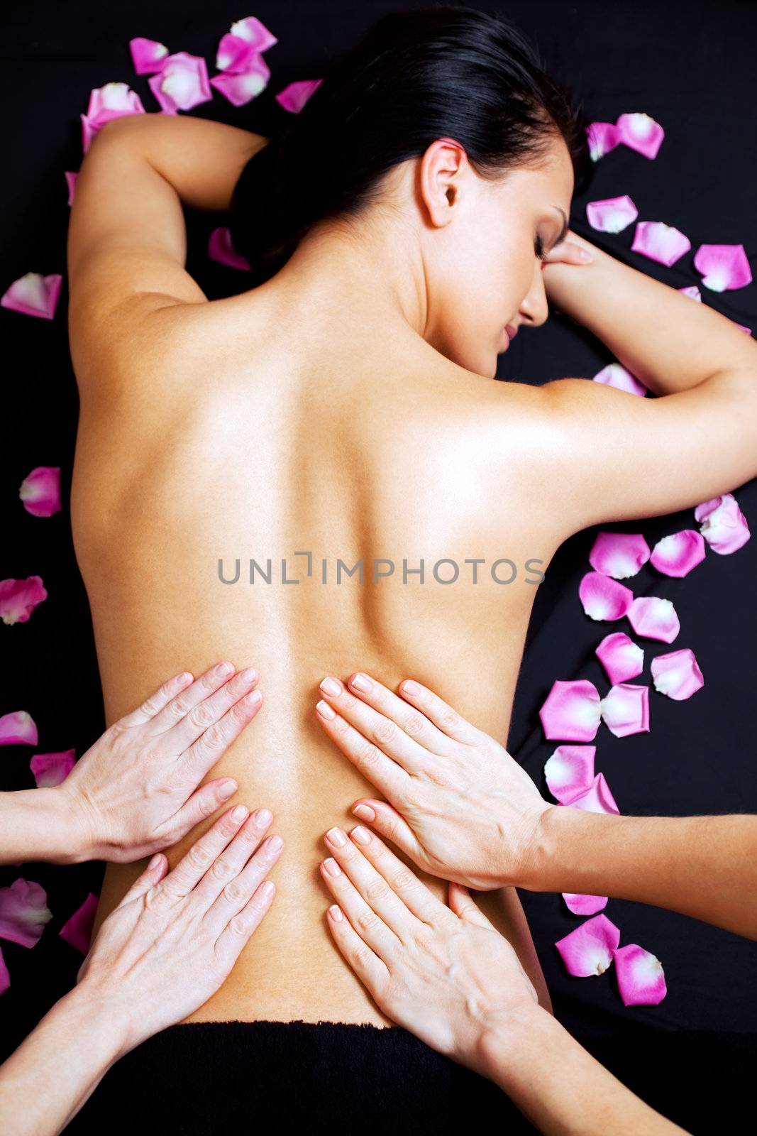 Four female hands giving a lower back massage of a beautiful woman