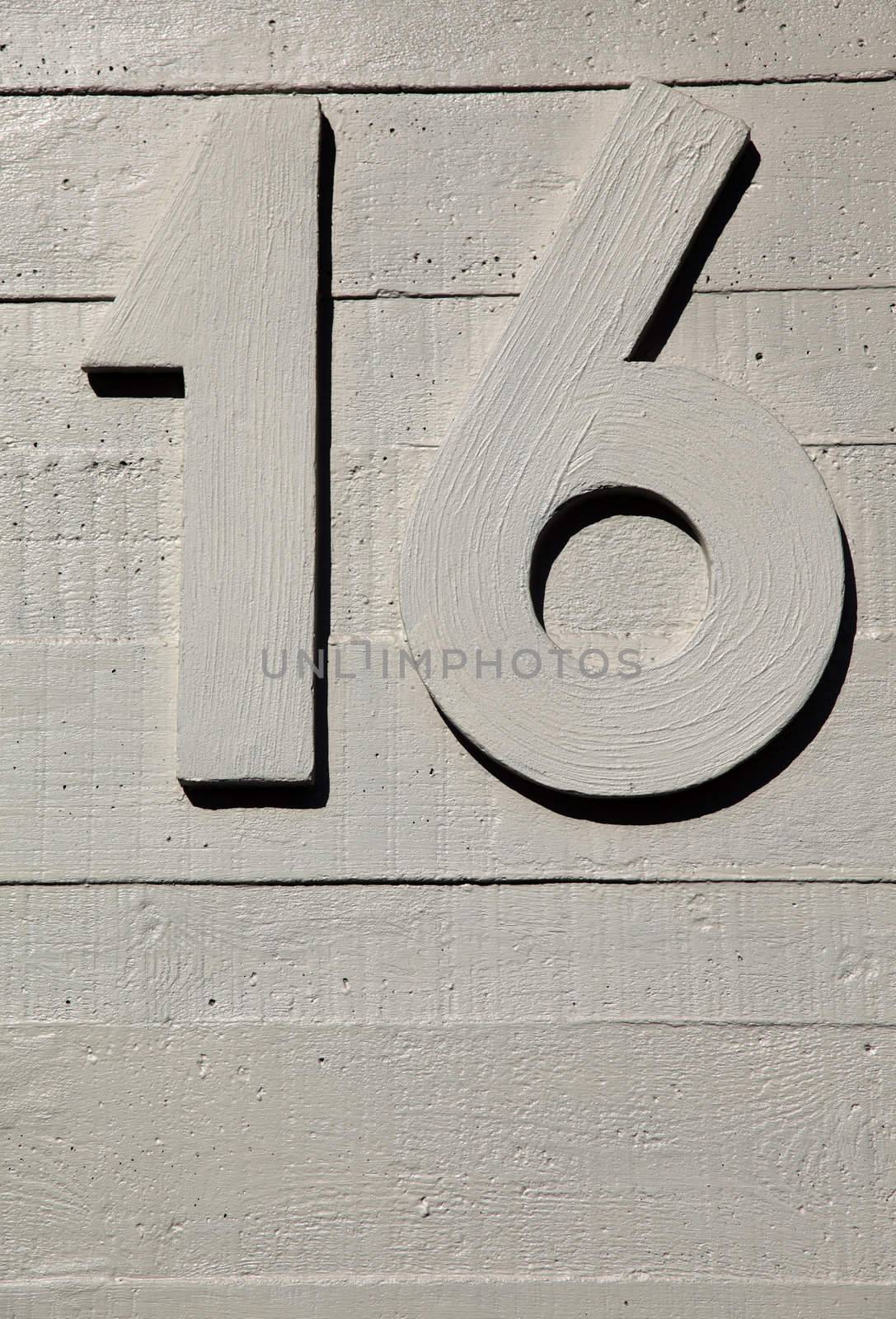 number sixteen on a concrete surface textured wall
