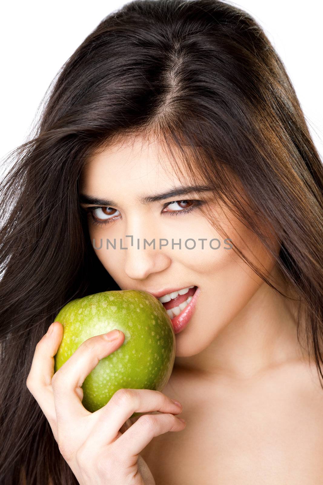 Close-up of beautiful young female biting granny smith apple, looking at camera