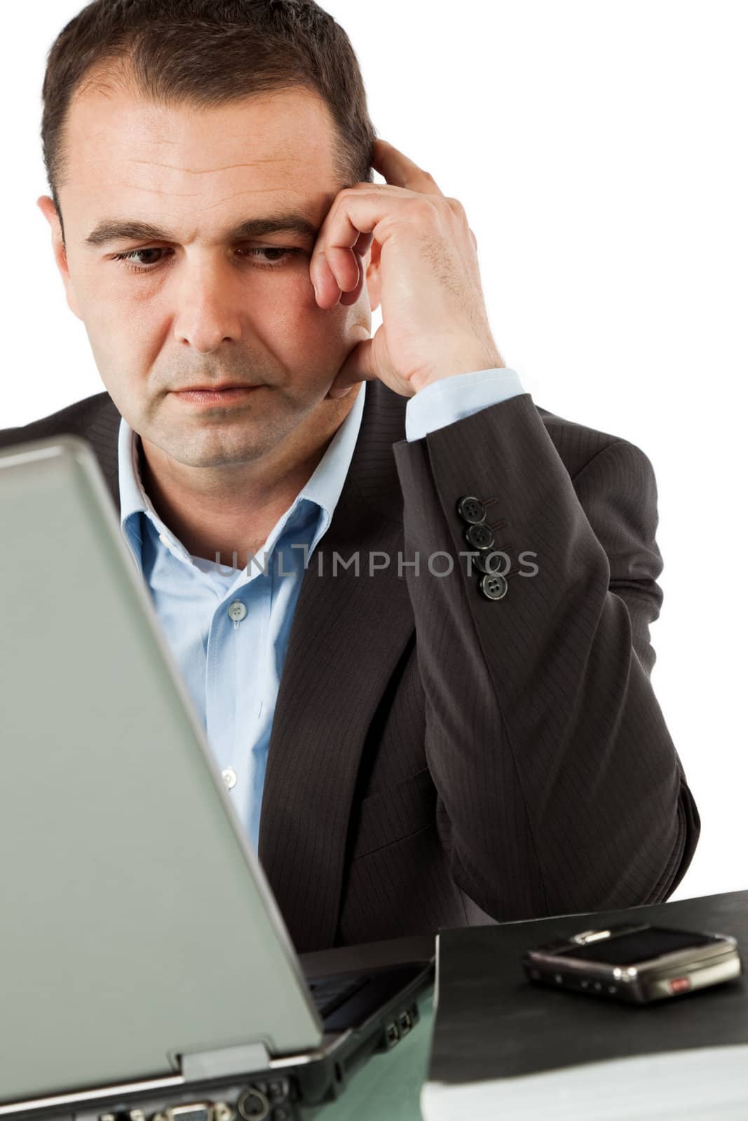 Businessman working behind laptop, looking at his cell phone thinking