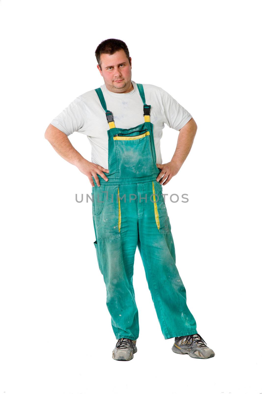 Male construction worker with dirty outfit looking at camera, arms on waist, isolated