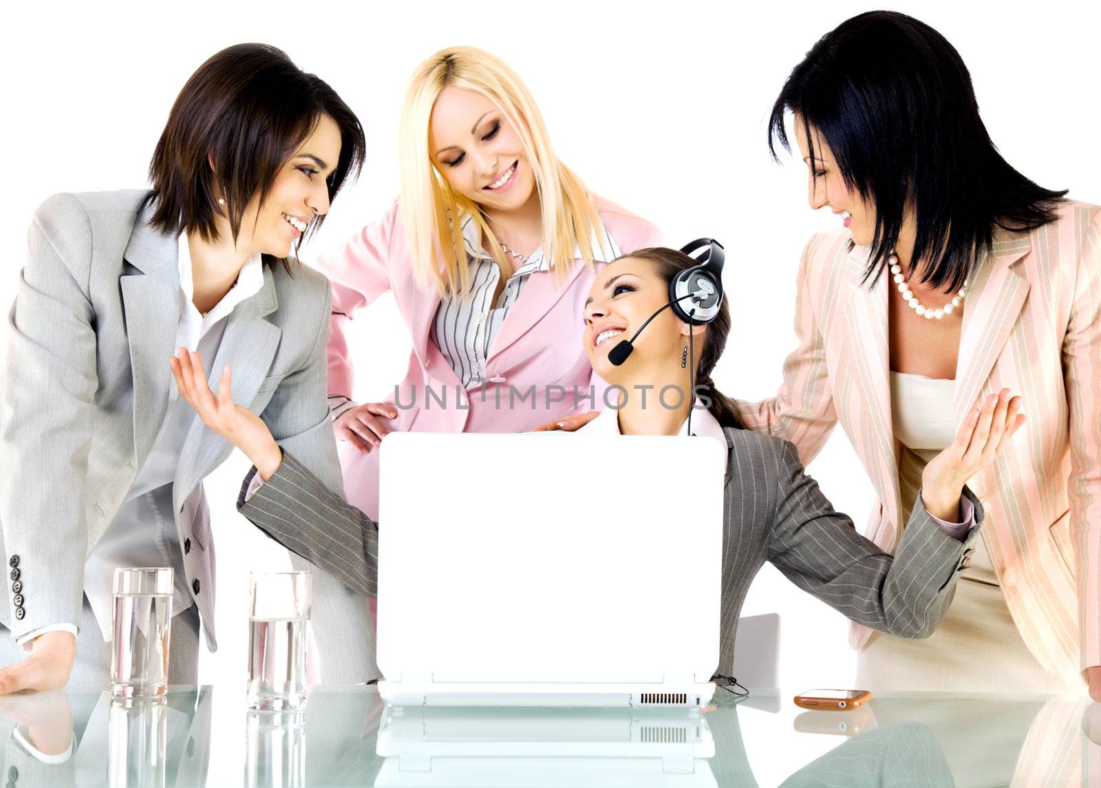 Successful team of four businesswomen smiling behind laptop, one with headset