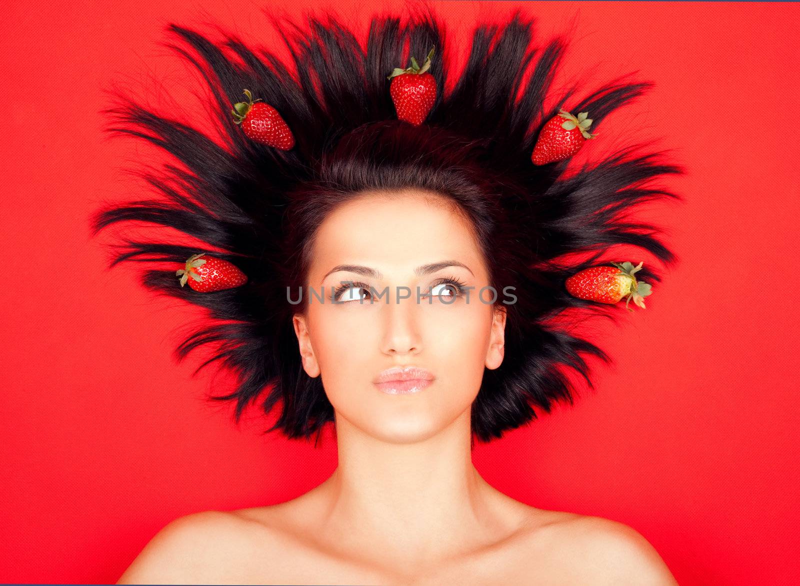 Portrait of young female with strawberries in her hair, on red background