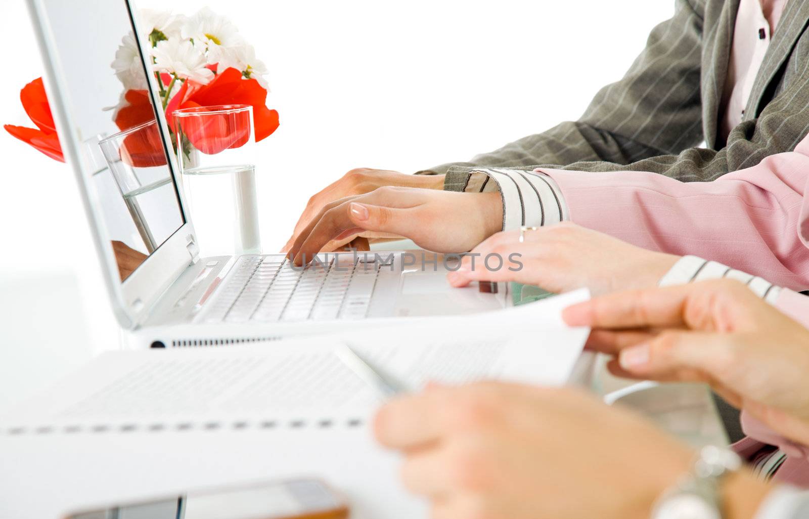 Close-up of female hands using laptop and working over documents on desk