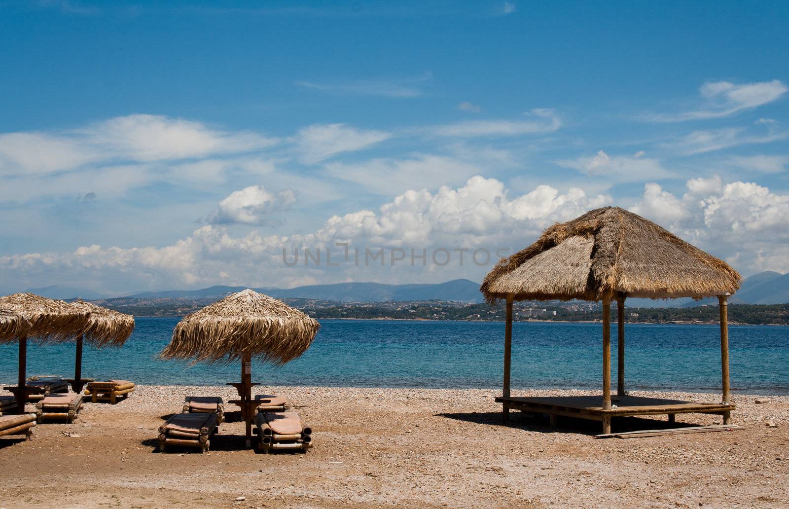 Beautiful beach with lounge chairs and straw umbrellas, Greece sea