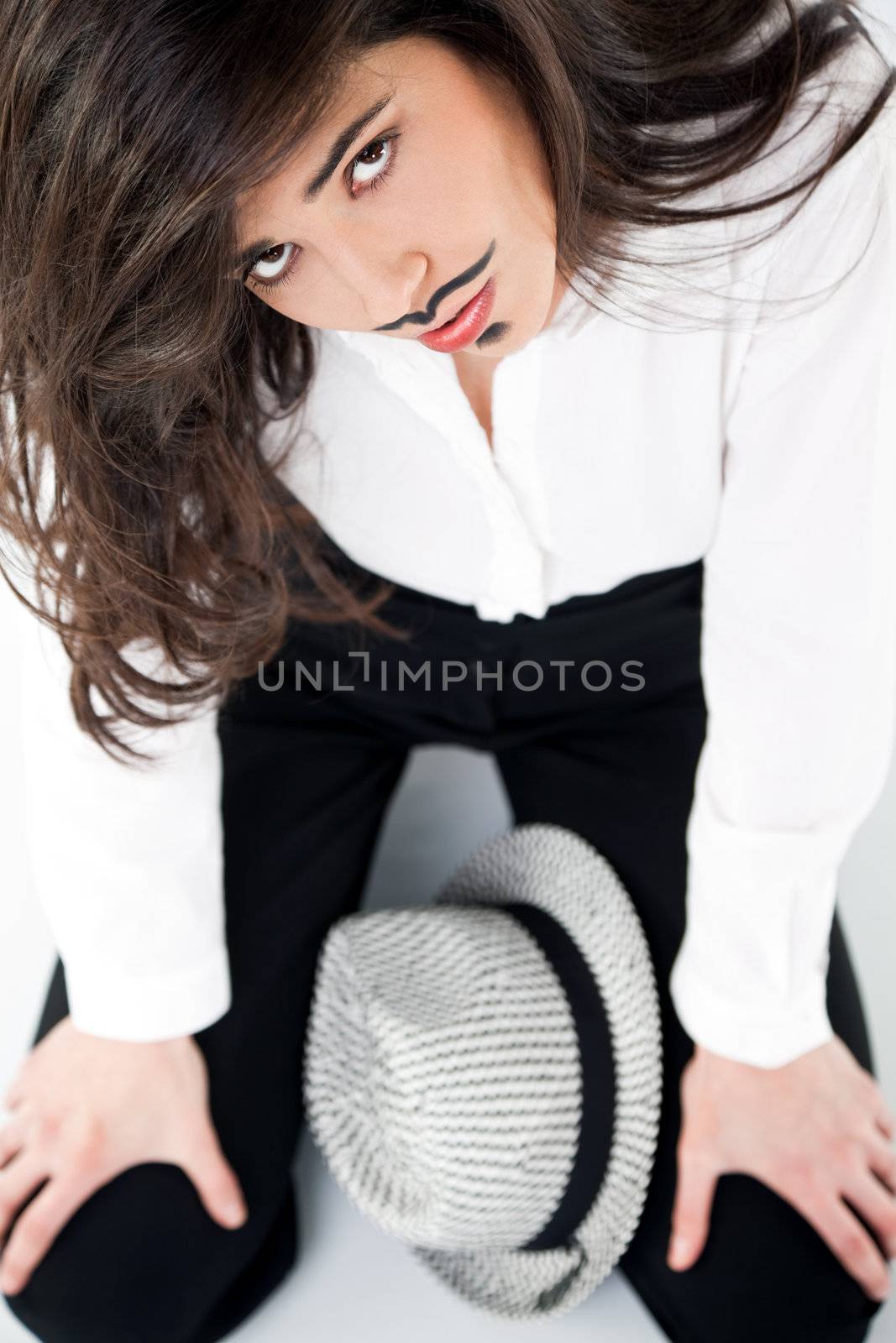 beautiful girl with moustache dendy makeup sitting with hat, looking up at camera