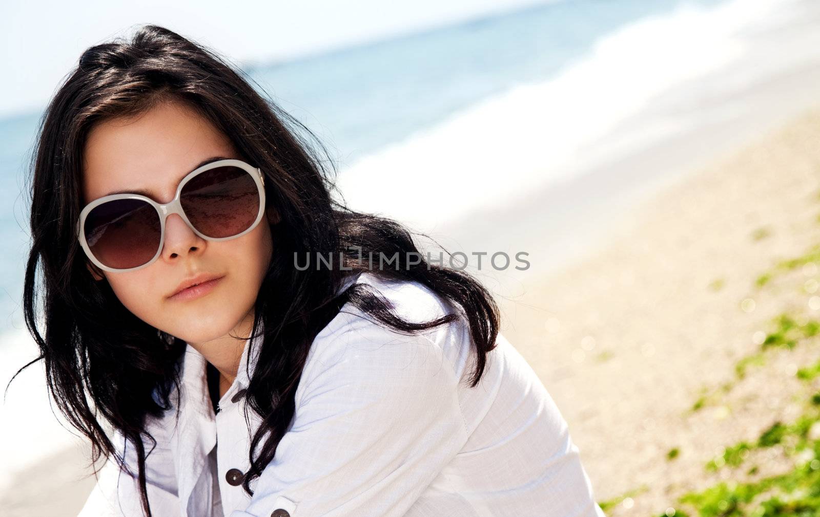 Portrait of beautiful female at the beach with shirt and sunglasses