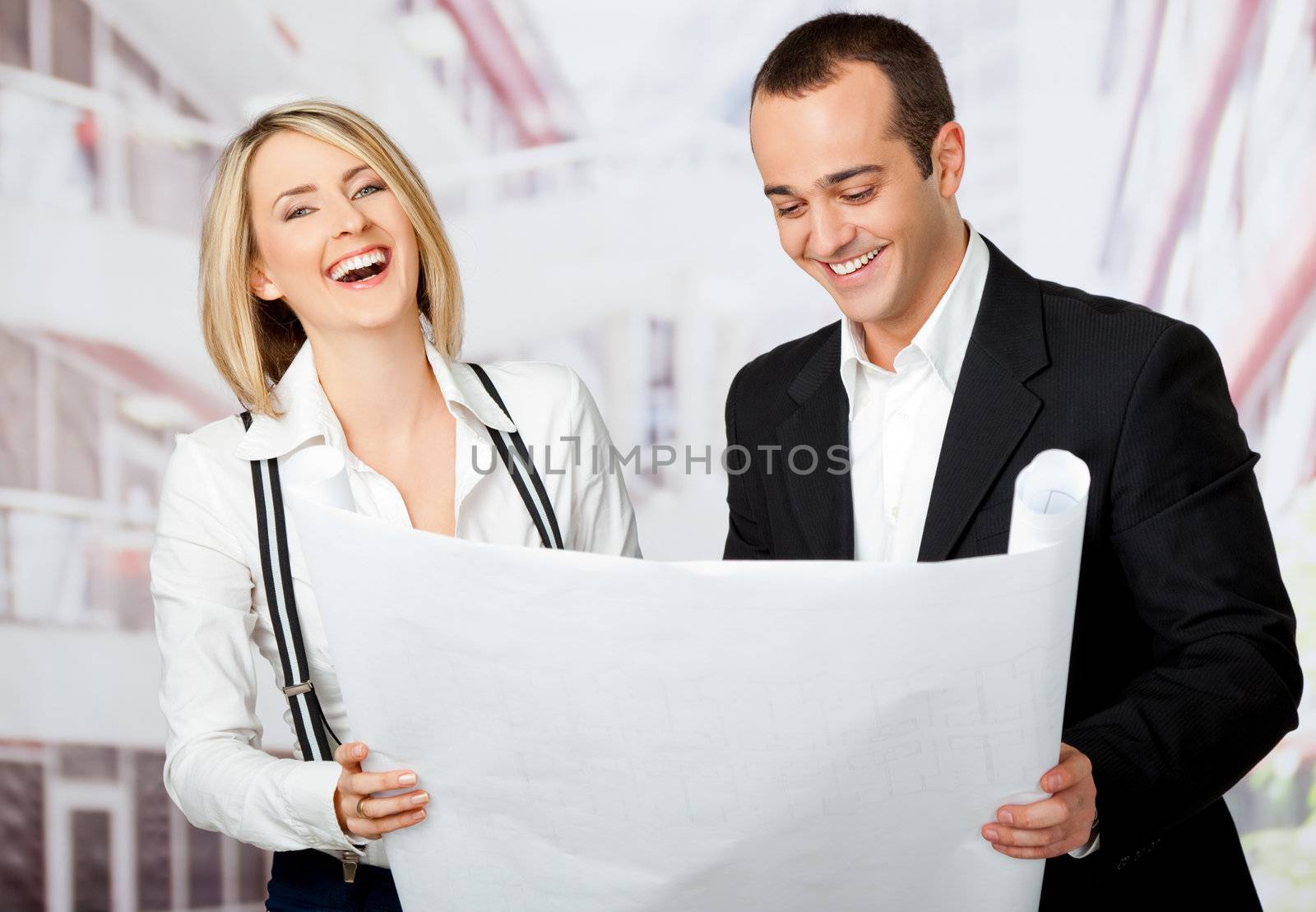 Two architects smiling, holding blueprint