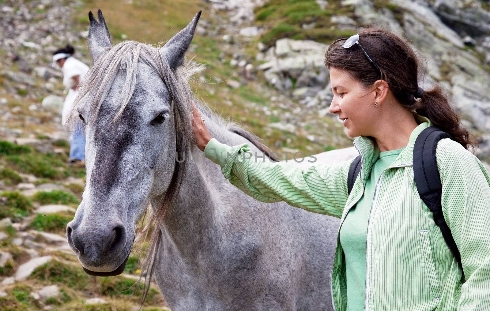 a young woman is petting a horse in the mountains