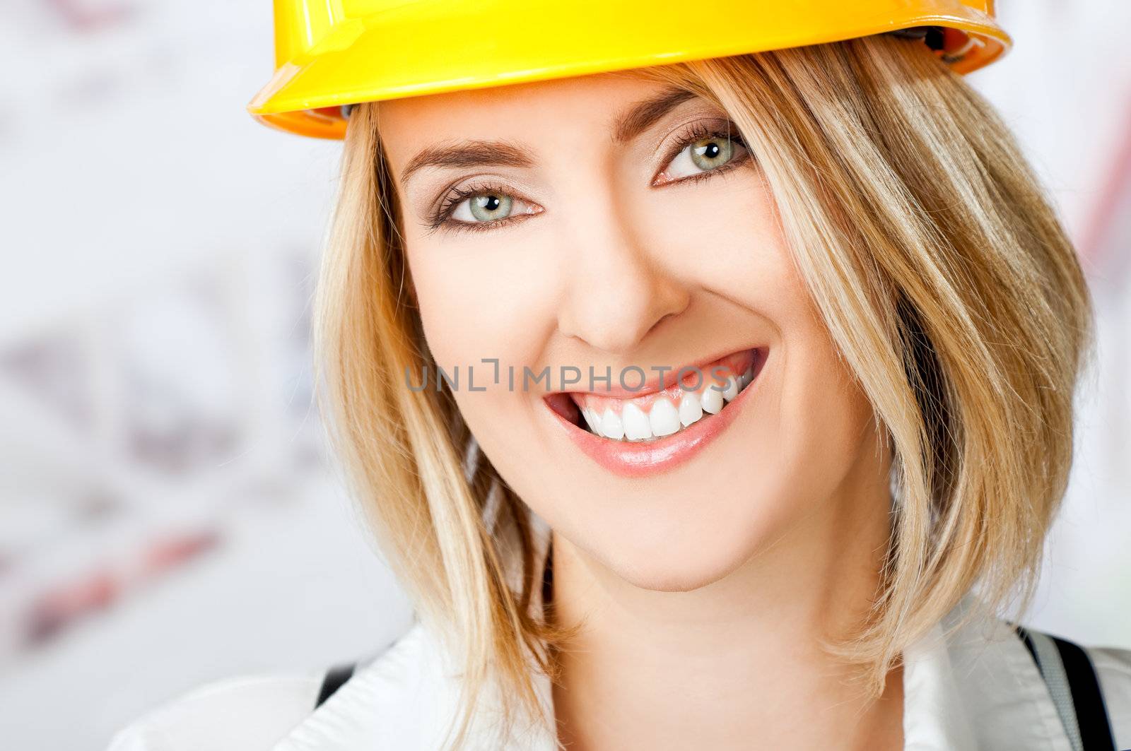 Portrait of beautiful smiling woman wearing yellow hardhat, looking at camera