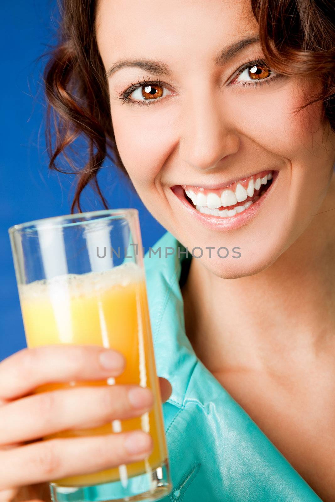 Close-up of beautiful smiling woman holding glass of orange juice
