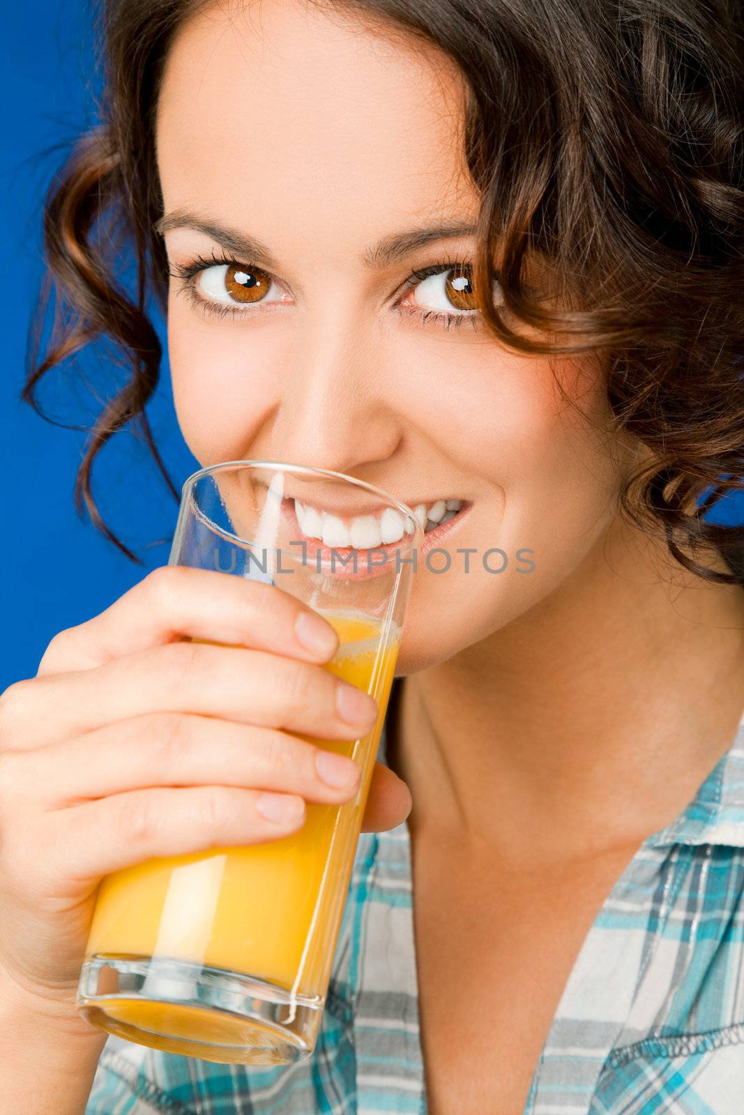 Portrait of beautiful woman drinking orange juice, smiling and looking at camera