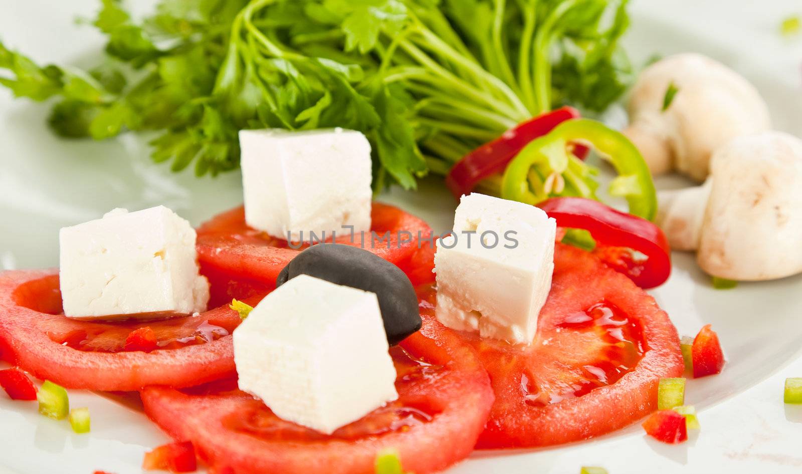 Close-up of tomato and cheese salad with parsley, mushrooms and pepper