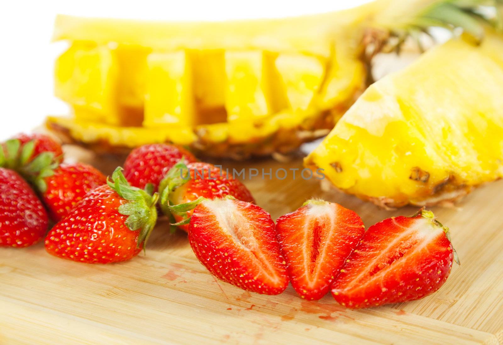 Close-up of fresh sliced strawberries and pineapple on wooden cutting board