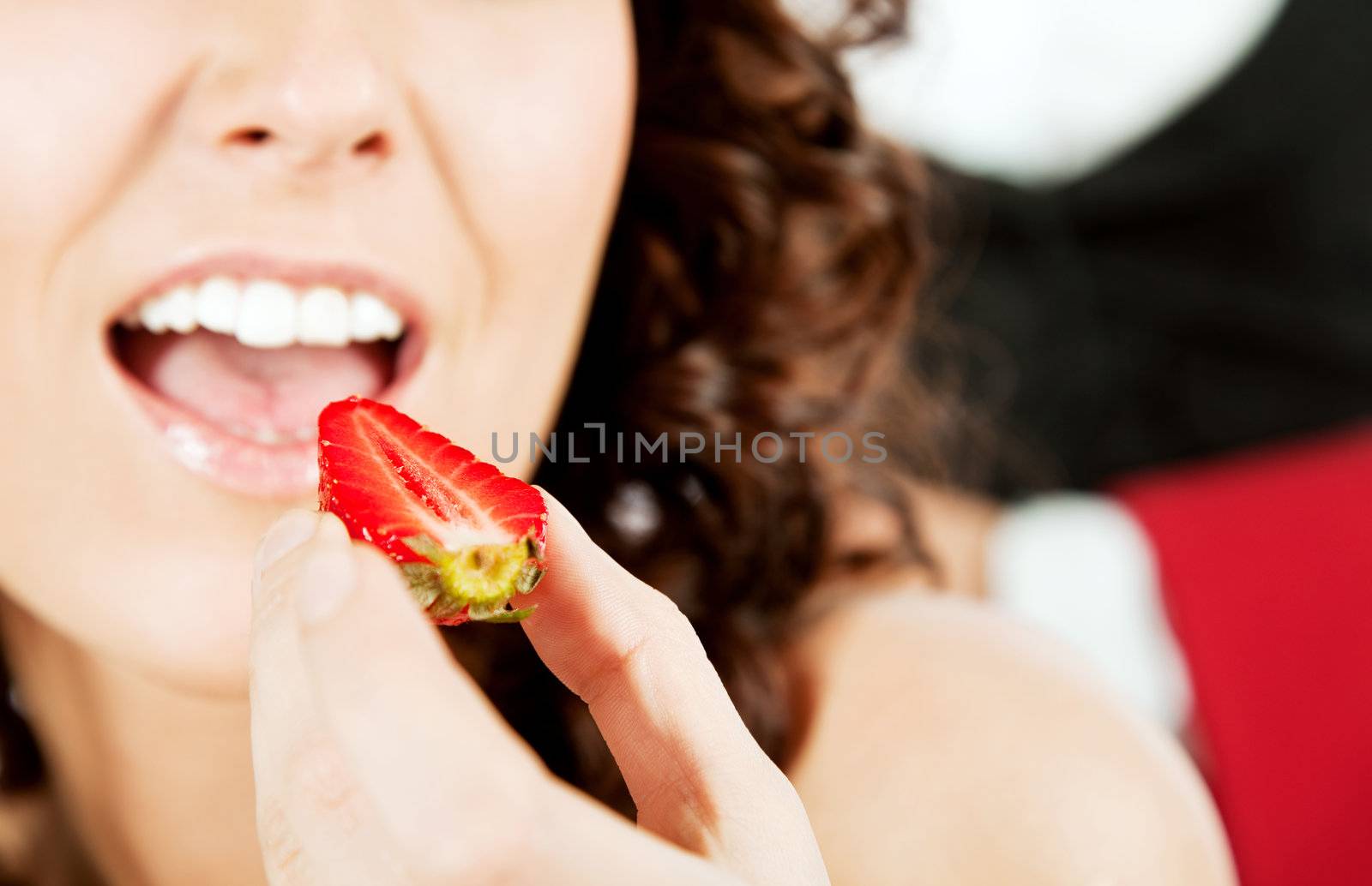 Close-up of a woman eating strawberry, focus on berry