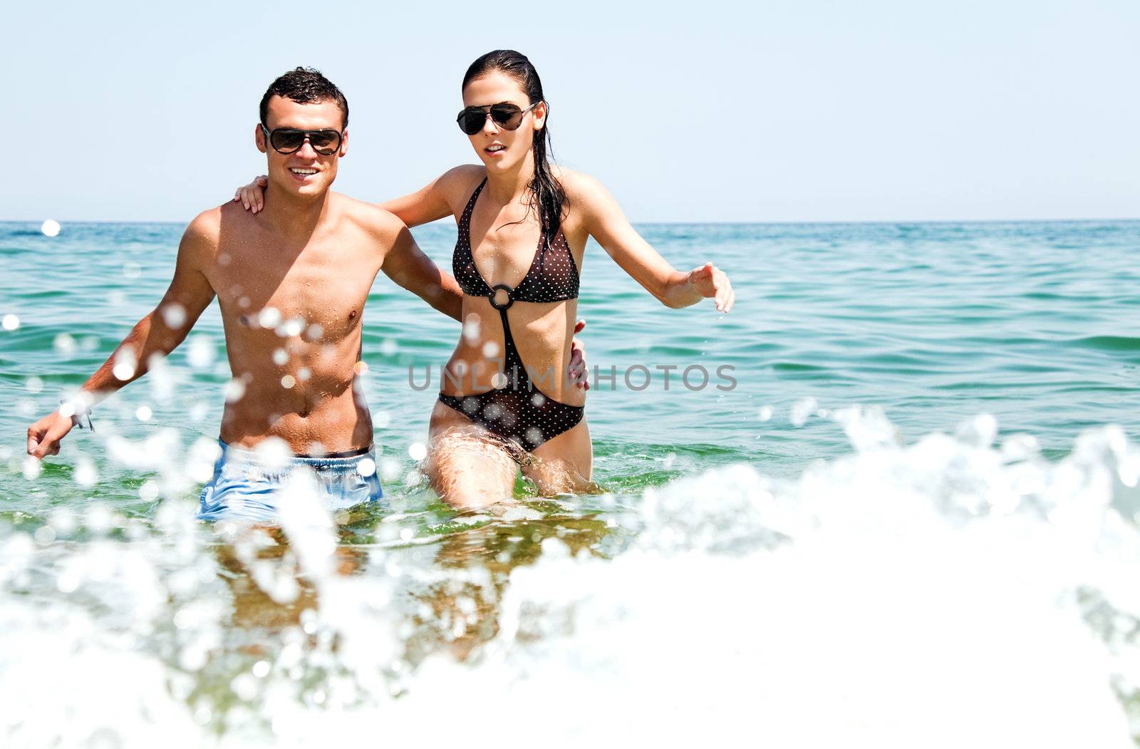 Young couple with sunglasses hugging and going out of sea