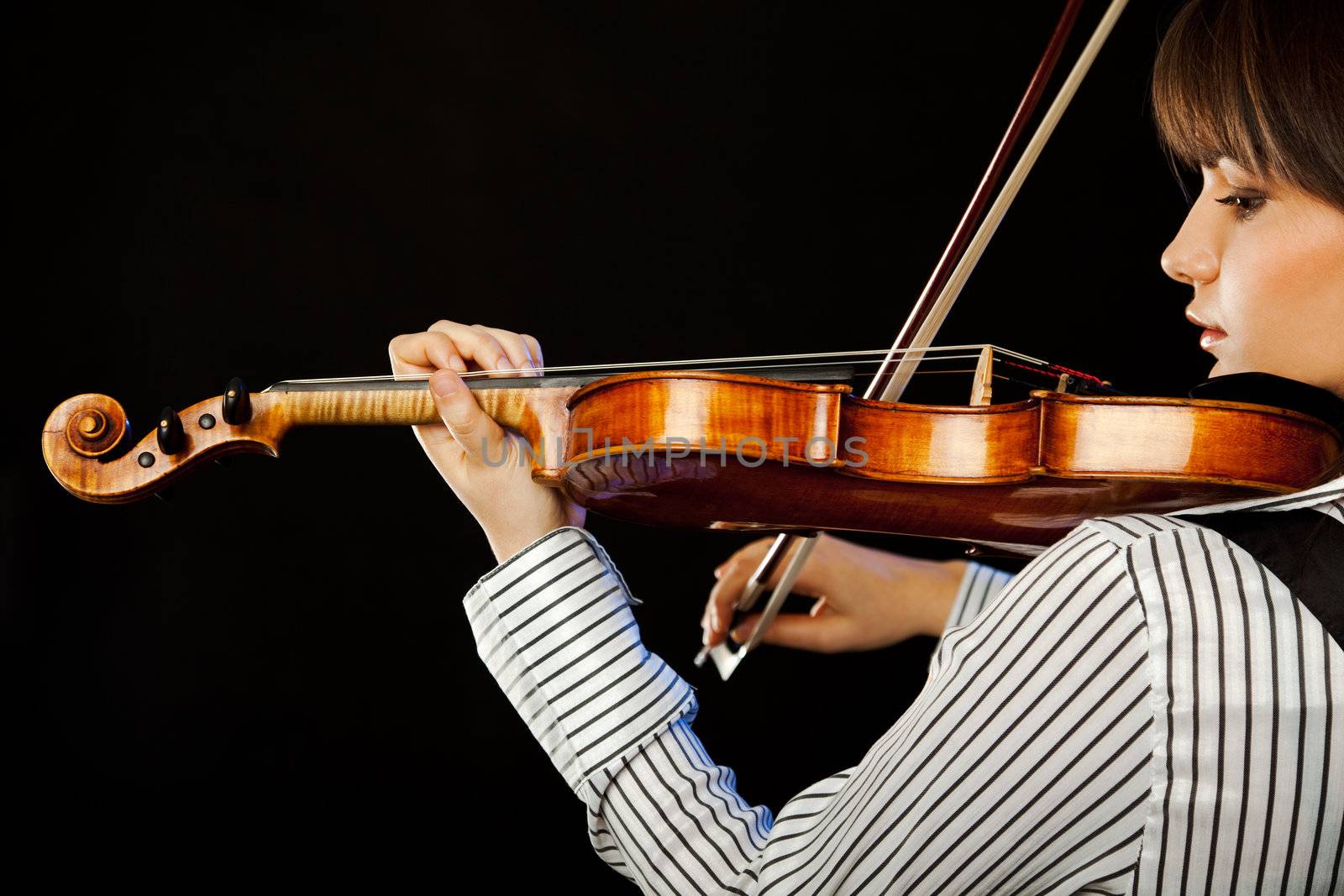 Beautiful female musician playing violin profile isolated on black