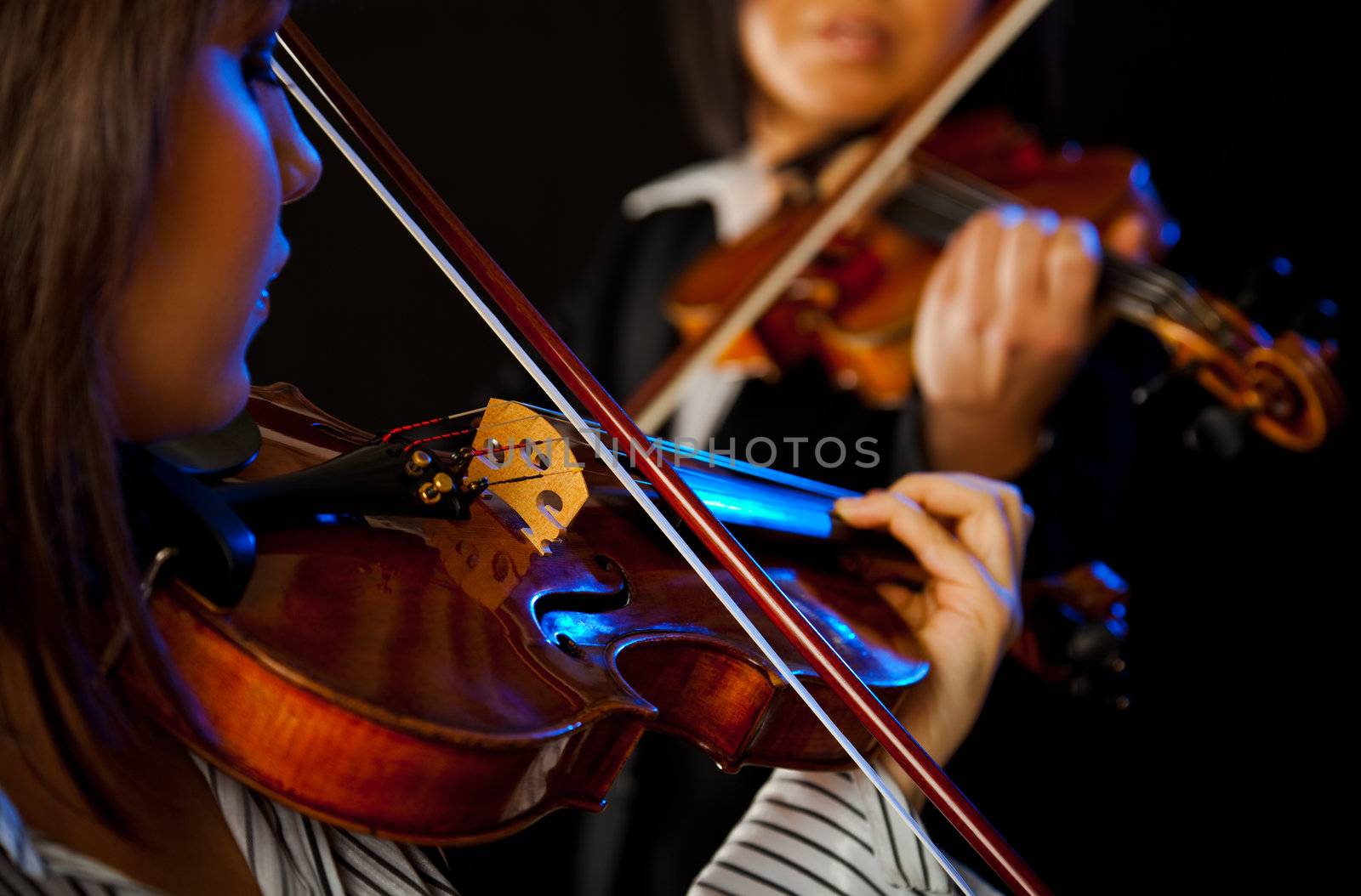 two violinists playing violins on a black background