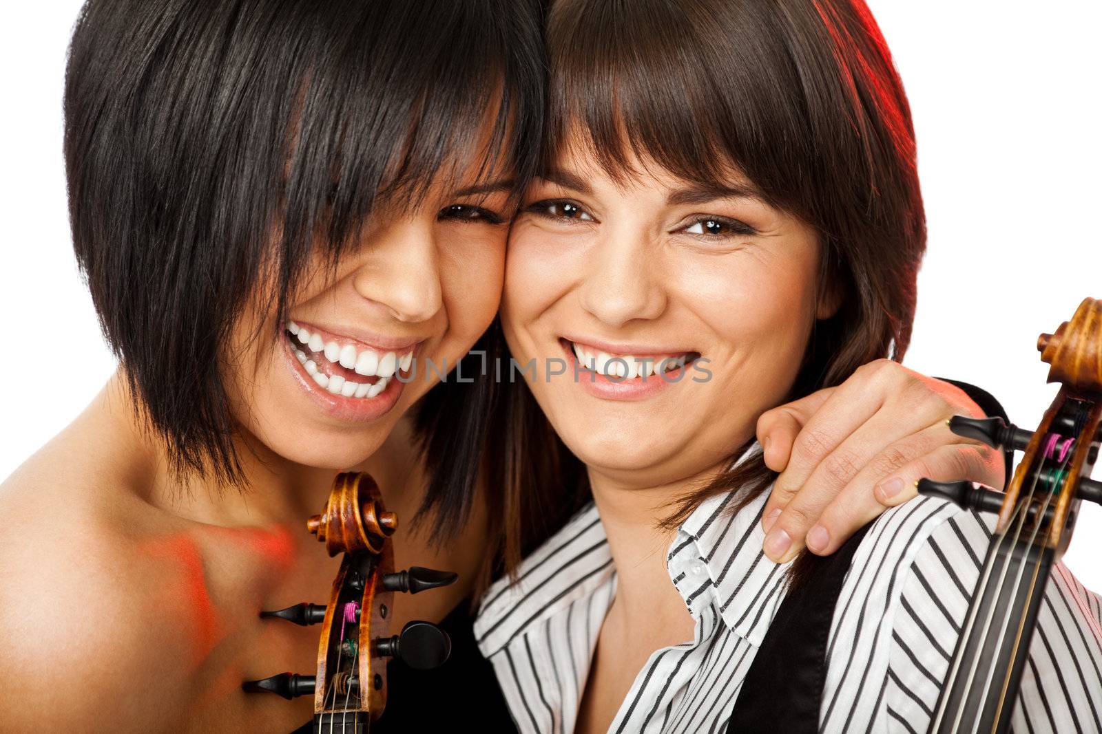 Two beautiful girls cheek-to-cheek smiling and hugging holding violins