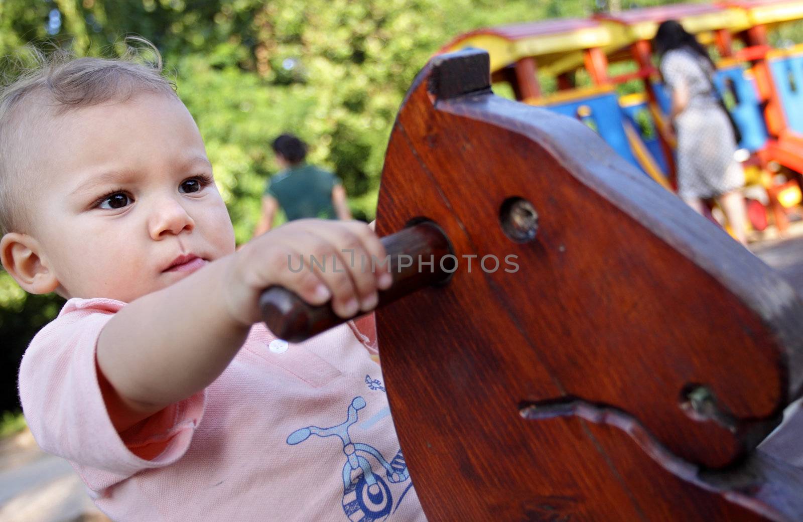 A portrait of a seriously looking child on a wooden horse swing