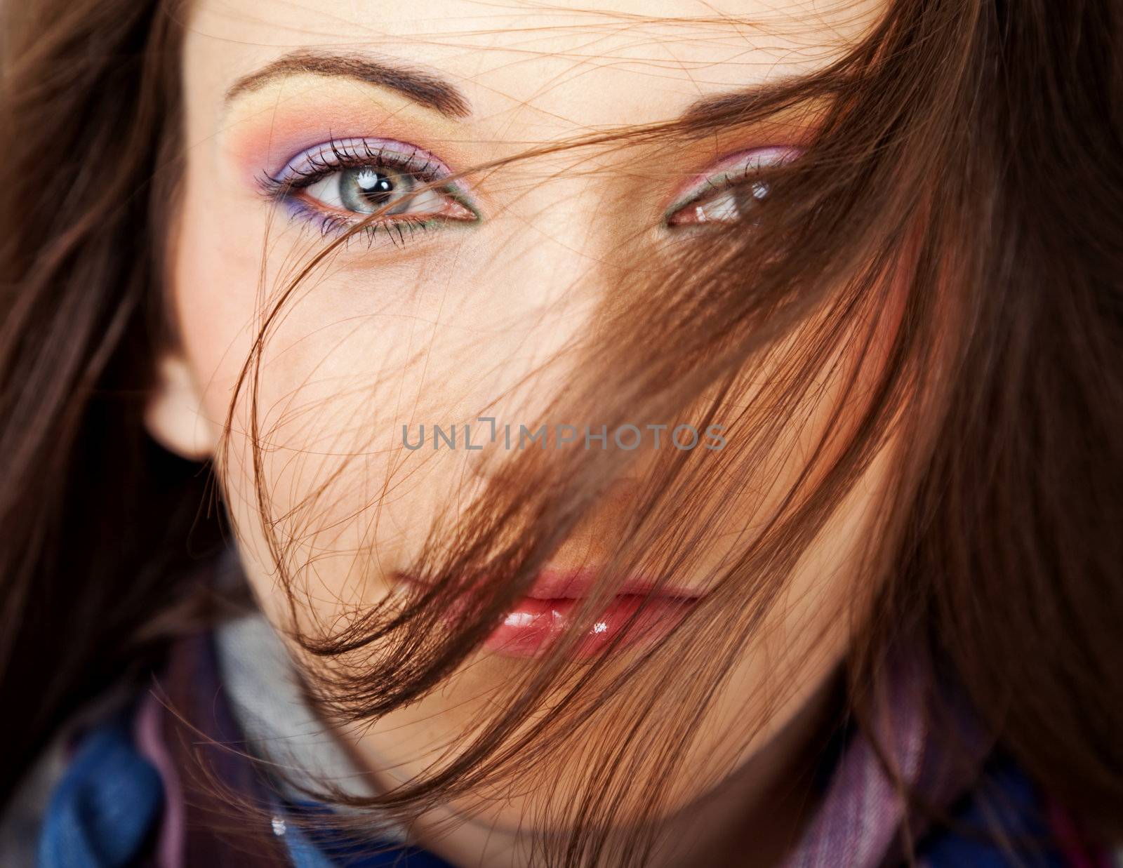 Close-up of a beautiful female face with hair blown over her face