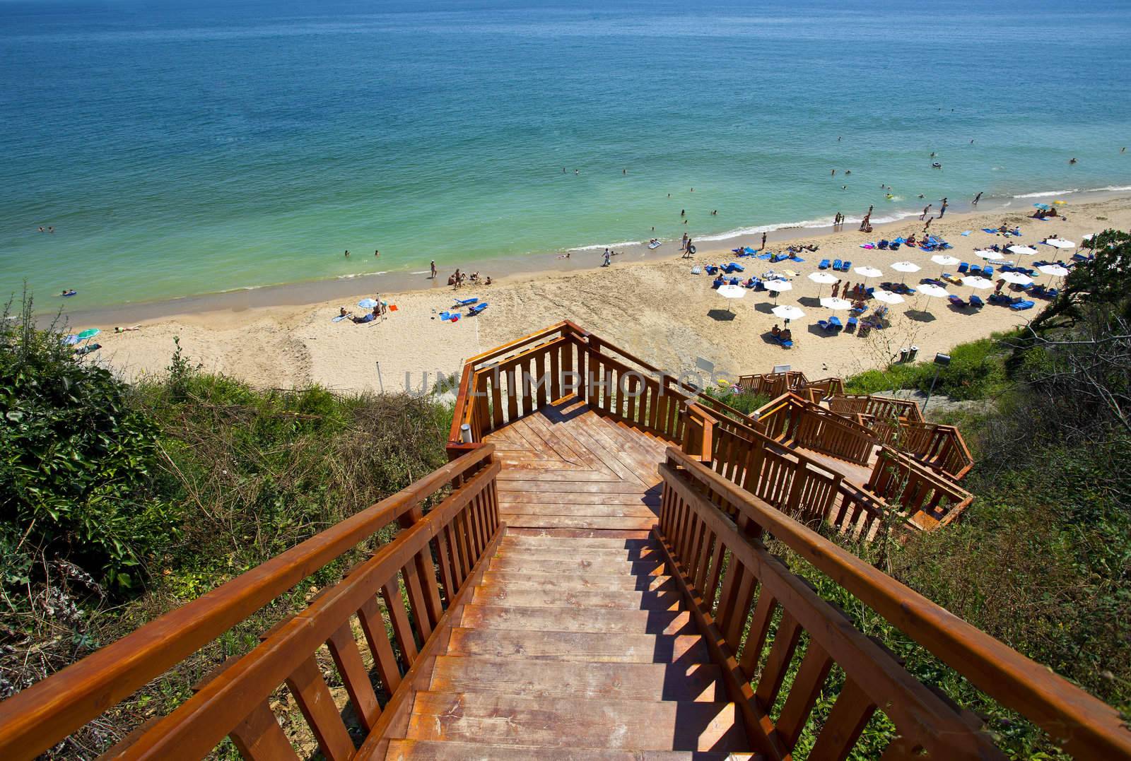Wooden stairway leading to a sand beach with umbrellas