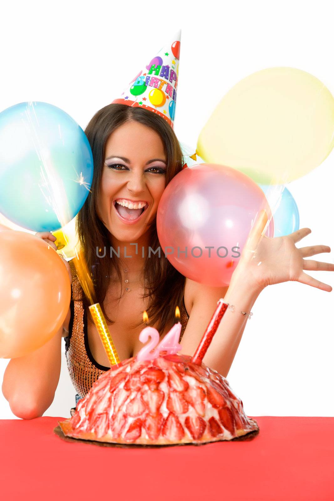 Beautiful happy female with party hat celebrating birthday over cake with candles