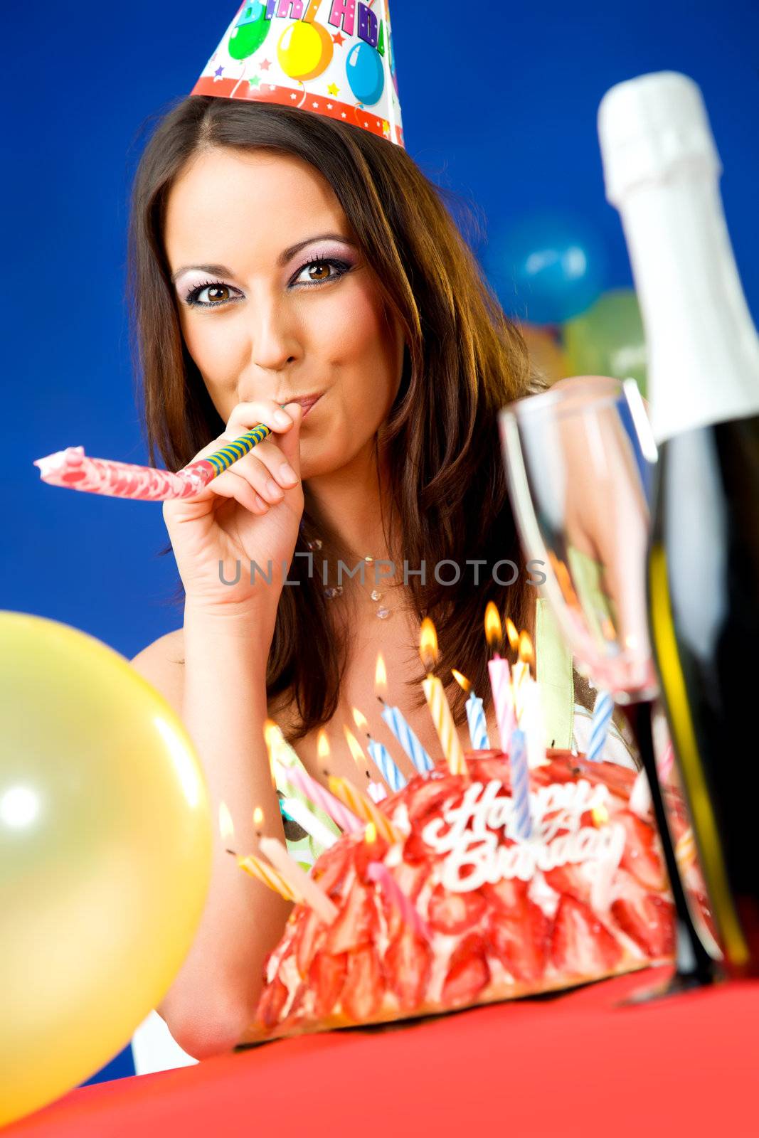 Beautiful happy female with party hat and horn blower celebrating birthday
