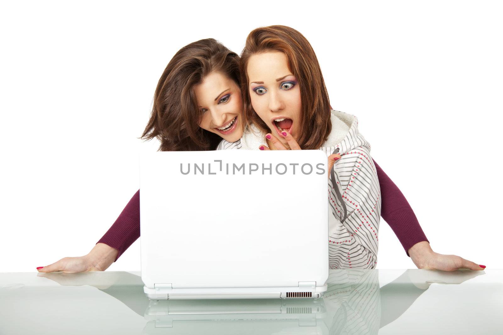 Two beautiful girls sitting behind a laptop very surprised