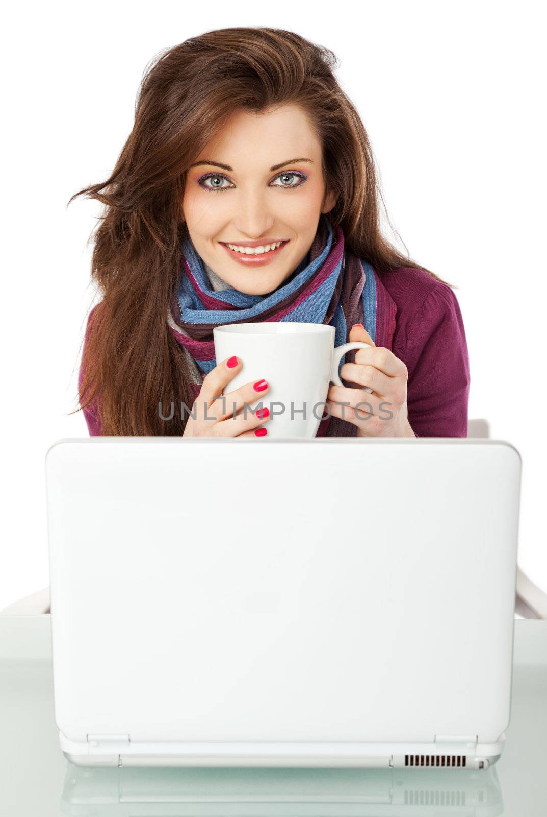 Young beautiful female sitting behind laptop, holding a cup smiling