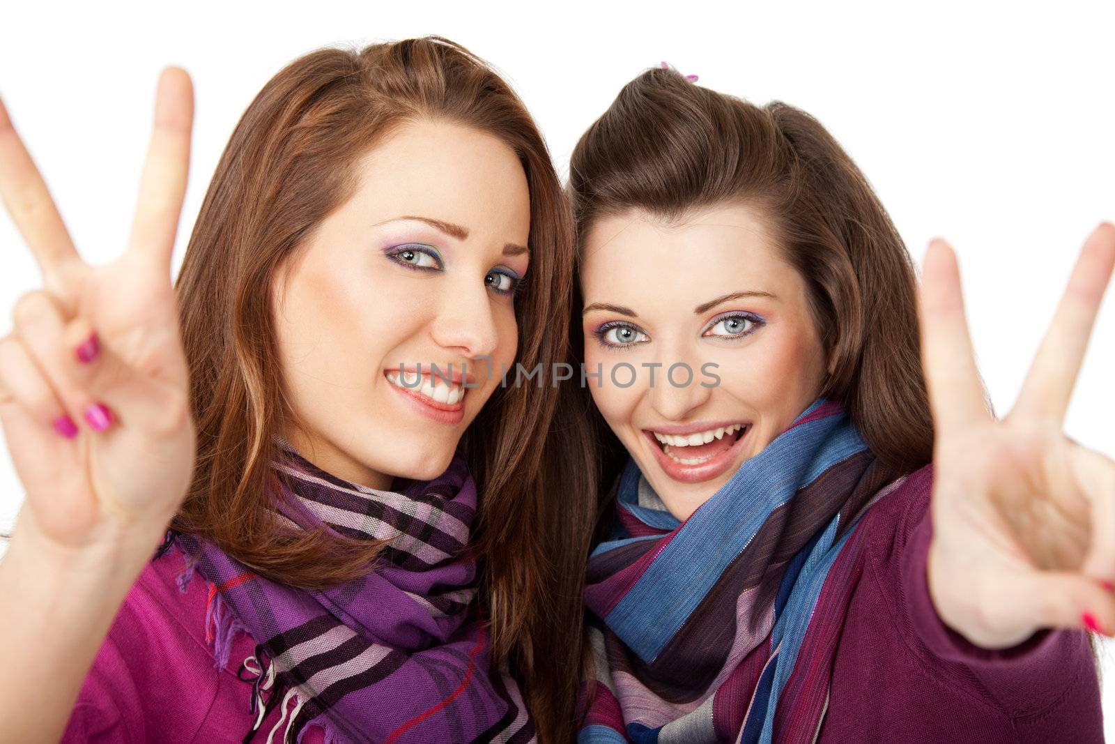 Two young beautiful girls smiling and showing peace signs